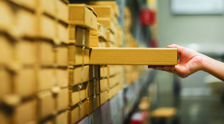 Hand pulling a box off of a warehouse shelf full of boxes